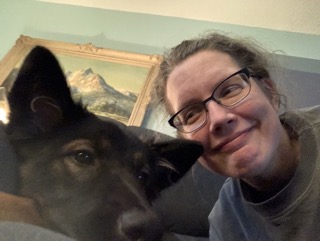 A sleepy German Shepherd cross puppy staring at nothing in particular with Donna smiling while looking at the dog.